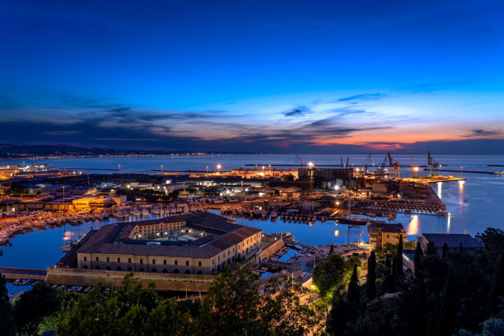 Getting Here A breathtaking aerial view of Ancona port at sunset, showcasing vivid colors and industrial docks.
